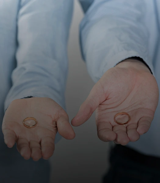 Two people holding wedding rings in their open palms, symbolizing divorce or separation.
