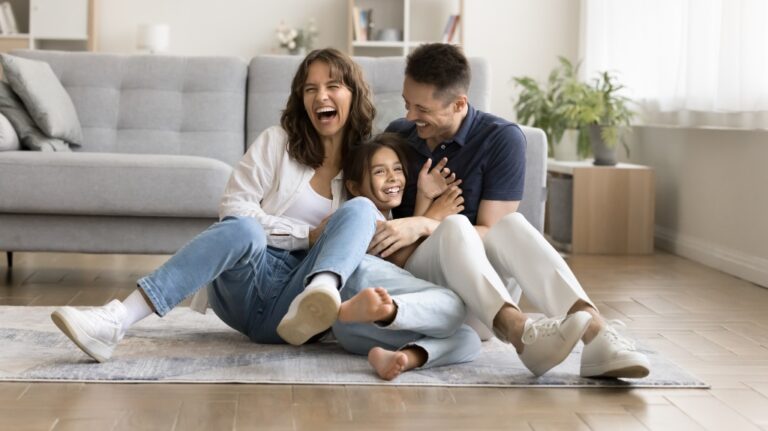 Cheerful excited parents tickling beloved kid girl