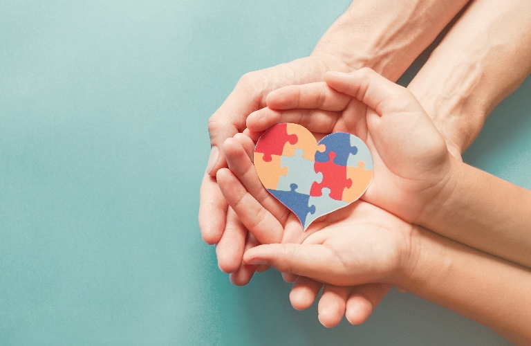 Adults and children's hands hold a heart-shaped puzzle