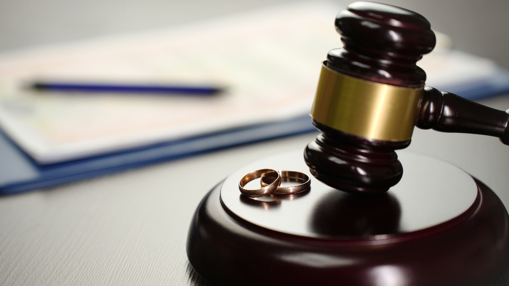 Judge gavel with wedding rings and divorce decree