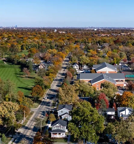 Aerial view of a city skyline featuring tall buildings, surrounded by trees and residential houses below.