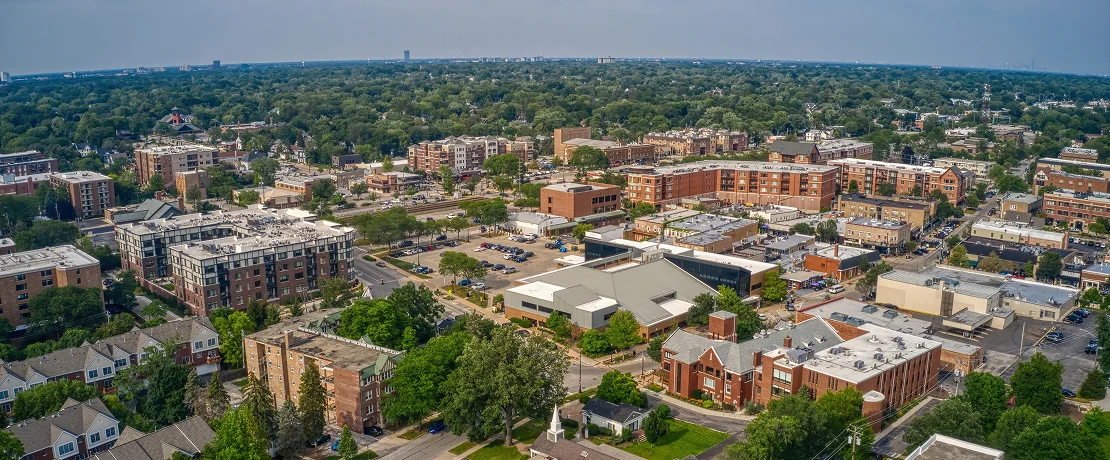 Aerial view of a city skyline featuring tall buildings, surrounded by trees and residential houses below.