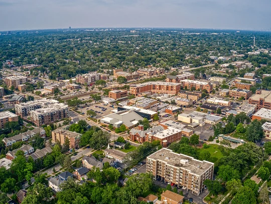 Aerial view of a city skyline featuring tall buildings, surrounded by trees and residential houses below.