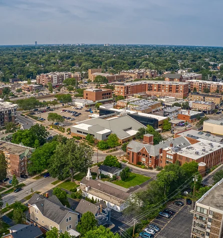 Aerial view of a city skyline featuring tall buildings, surrounded by trees and residential houses below.