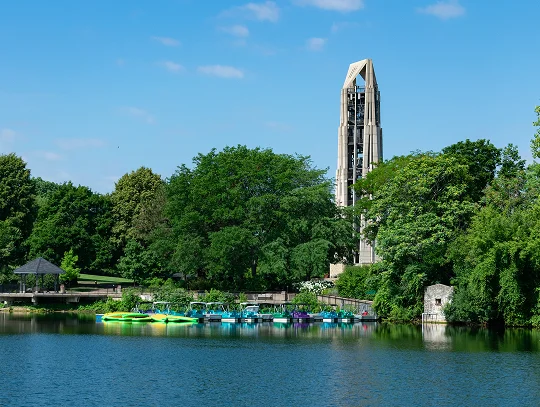 A serene body of water reflecting the sky, surrounded by lush greenery and distant hills.
