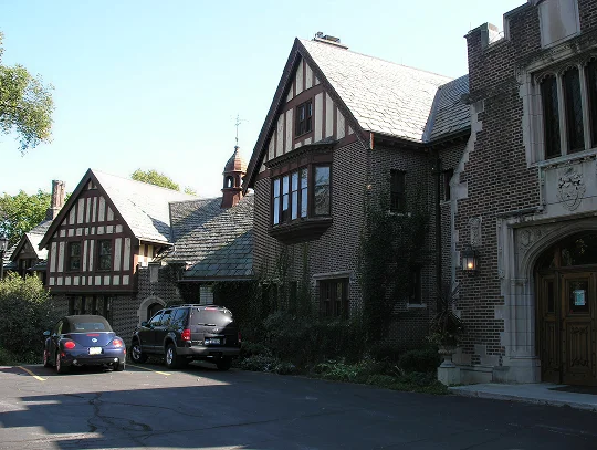 A large house with a car parked in front, showcasing a spacious driveway and well-maintained exterior.