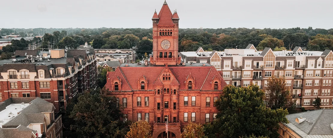 A red brick building featuring a prominent clock tower against a clear sky.
