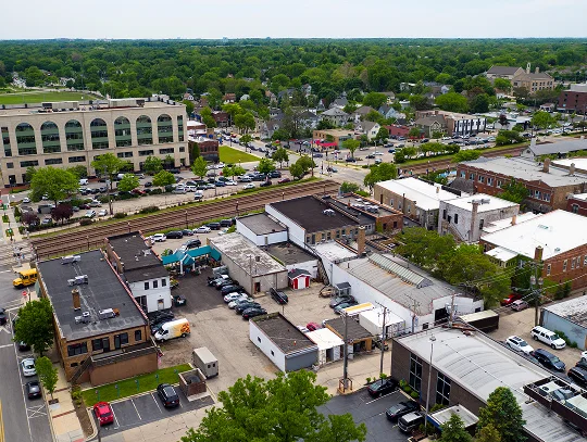 Aerial view of a bustling cityscape, showcasing buildings, streets, and green spaces under a clear blue sky.