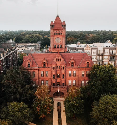 A red brick building featuring a prominent clock tower against a clear sky.