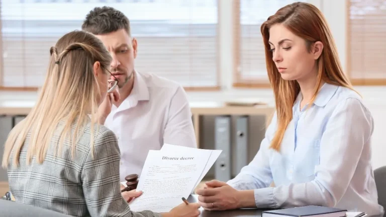 Three adults in a formal office setting reviewing a divorce decree document.