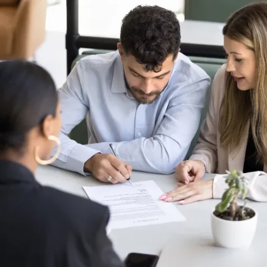 Married couple signing paperwork relating to the marital home during a divorce